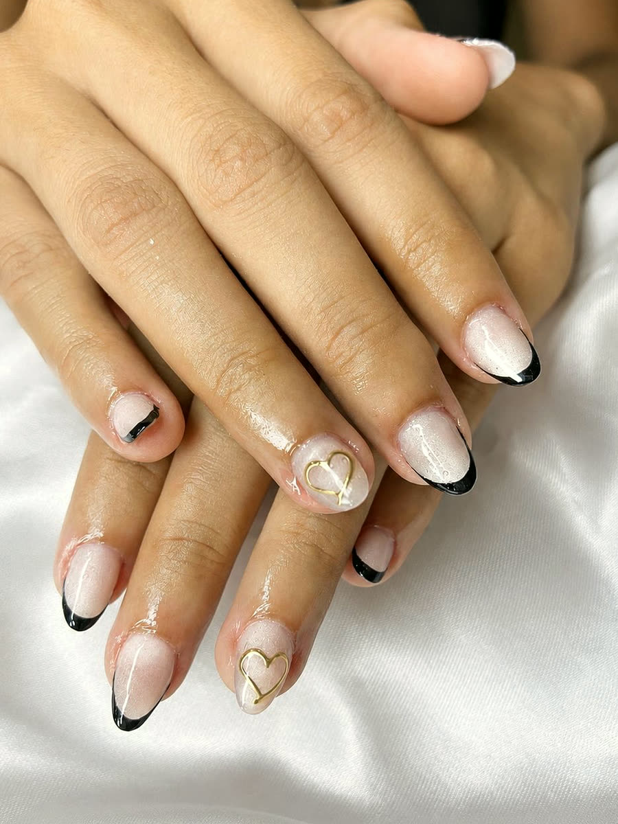 Francesinha preta fina em unhas nude, com coração dourado desenhado